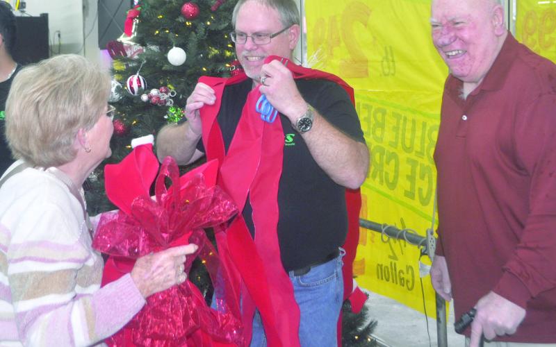 Kathy Hagler drapes the ceremonial ribbon over Billy Dickinson, the current full-time manager for H&amp;amp;S Discount Foods during the 50-year ribbon cutting ceremony. Wayne Hagler finds the entire situation humorous as the three share a moment as friends. Dennis Phillips | The Light and Champion