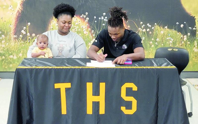 Terry Bussey surrounded by friends and family signs his letter to commit to the Texas A&amp;amp;M University athletic program. Dennis Phillips | The Light and Champion