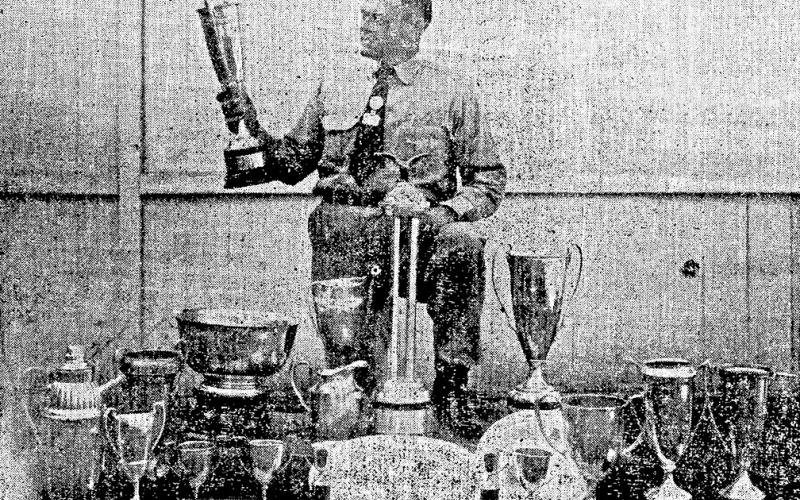 Shelby County Hounds Are Cup Winners — In the above picture John Schillings, well known to foxhunters throughout the southwest, is shown examining some of the trophies won by Shelby County fox hounds at various shows in this and other states. John is one of the ardent hunters in East Texas and it is said that he’ll go any place any time to attend a hunt.Shelby County hounds have been up against the best in the land and the picture is proof that they have been able to hold their own wherever entered.