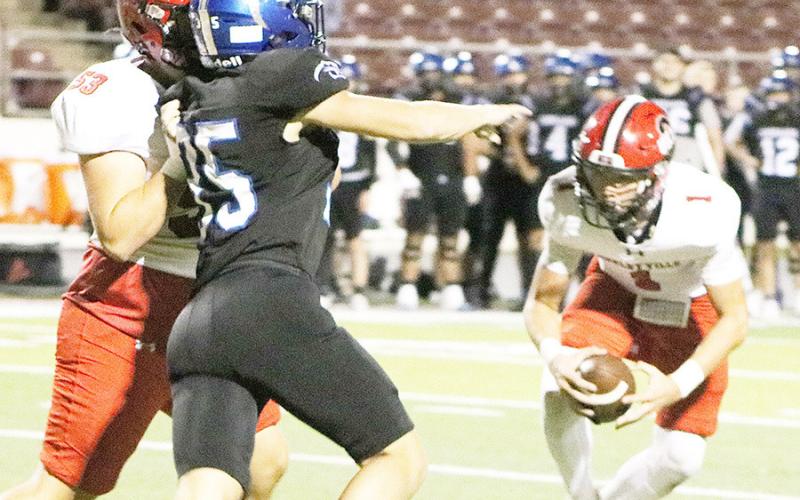 Shelbyville’s Trace Sims (53) fends off a defender as quarterback Gavin McDonald (1) tries to make a play in the Dragons’ playoff game against the Leon Cougars. Dragon Yearbook | Light and Champion