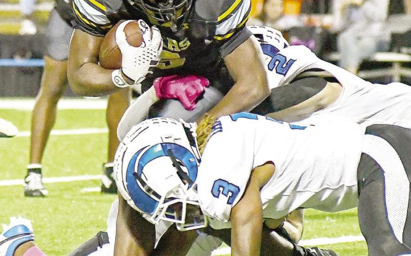 Jeffrey Richardson, Timpson running back, tries to break free of the grasp of Jacob Gatlyn (3) and Cooper Bragg (2) of the Joaquin Rams as the cross-county opponents faced off last Friday night. Timpson ISD | Light and Champion