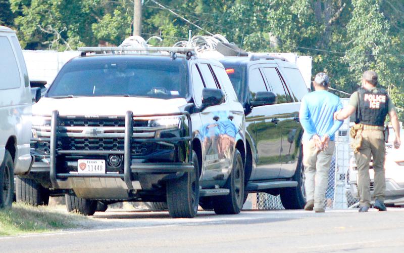 An agent with ICE leads one of the occupants of a van stopped on Highway 7 outside of Center to a waiting law enforcement vehicle. David Danley | Light and Champion