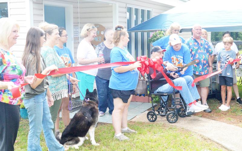 Dr. Robert Hughes cuts the ribbon for the open house held last Saturday for Happy Tails Adoption Center. Hughes donated his former veterinary practice building to the agency to give it a home. Zack Clark | Light and Champion