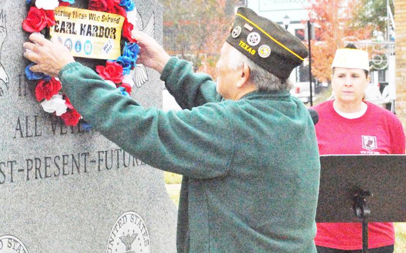 Post Life Member Larry Jones hangs a wreath in honor of Pearl Harbor Day at the Shelby County veteran’s memorial on the historic courthouse square while VFW Post 8904 Quartermaster Mary Roberts looks on. The Japanese attack on Pearl Harbor on Dec. 7, 1941, marked the official entry of the United States into World War II. David Danley | Light and Champion