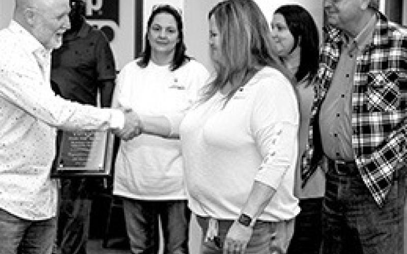 Paul Wright, owner of Wright Chrysler Dodge Jeep Ram dealership in Center accepts a Chamber of Commerce 20th Anniversary celebration plaque from Chamber Ambassador Brandy Filz Friday at the dealer’s open house while General Manager Jeff Baker (behind Filz) watches.