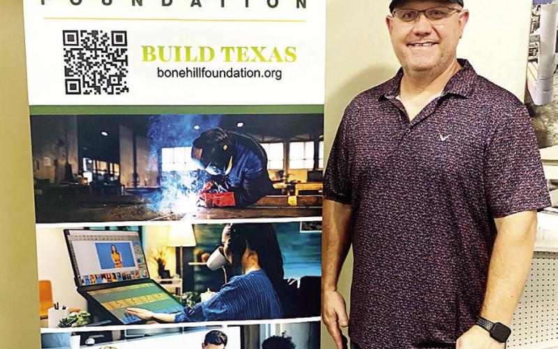 Robbie Dubea of Center Hallmark Fixtures stands beside a Bone Hill Foundation banner that will rotate among area businesses to help promote vocational education training in Shelby County. Submitted | Light and Champion