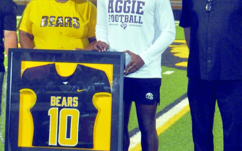 Shy’ Kuirra Bussey, sister, and Head Coach Kerry Therwhanger stand center field with Terry Bussey during the retirement ceremony of the #10 jersey worn by Bussey all four years as a Timpson Bear. Bussey led the Bears to their first State Championship title in 2023 and now plays for the Texas A&amp;amp;M Aggies. Dennis Phillips | Light and Champion