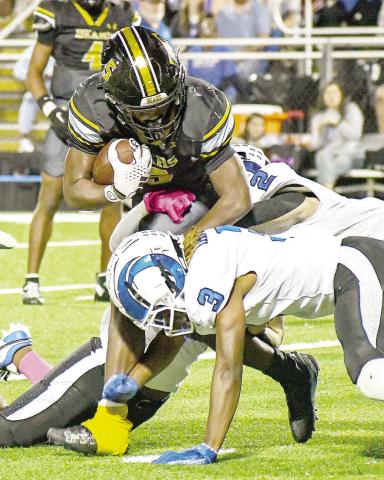 Jeffrey Richardson, Timpson running back, tries to break free of the grasp of Jacob Gatlyn (3) and Cooper Bragg (2) of the Joaquin Rams as the cross-county opponents faced off last Friday night. Timpson ISD | Light and Champion