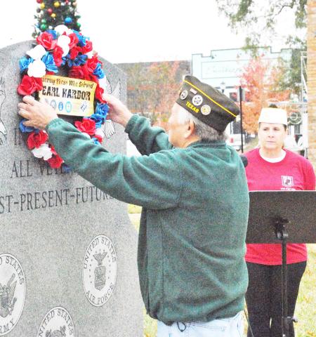 Post Life Member Larry Jones hangs a wreath in honor of Pearl Harbor Day at the Shelby County veteran’s memorial on the historic courthouse square while VFW Post 8904 Quartermaster Mary Roberts looks on. The Japanese attack on Pearl Harbor on Dec. 7, 1941, marked the official entry of the United States into World War II. David Danley | Light and Champion